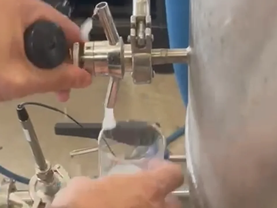 Cropped close-up of a hydrogen-rich sample being collected from a sanitary outlet into a clear cup.